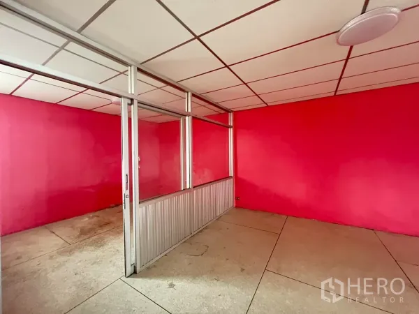 Shophouse for rent in Watthana, Bangkok - Upper-floor room with pink walls and an aluminum-framed sliding glass partition.