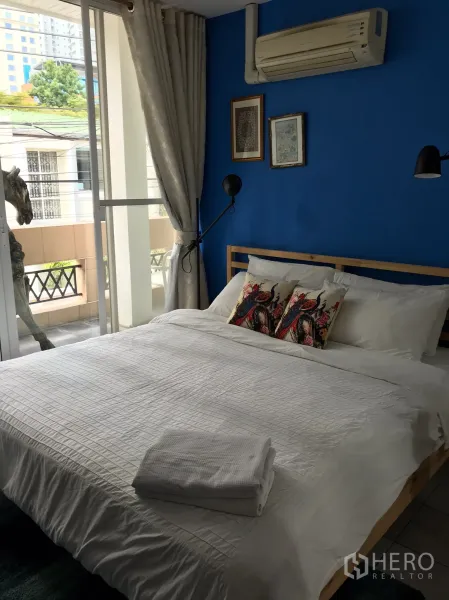 联排别墅 出租在Khlong Toei, Bangkok - 带蓝色特色墙的大窗卧室，配有空调。