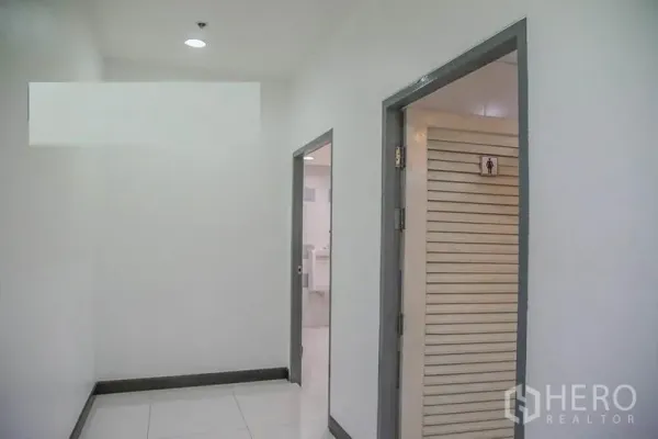 Office Space for rent in Bang Na, Bangkok - Hallway leading to restrooms with tiled floors inside the office building.