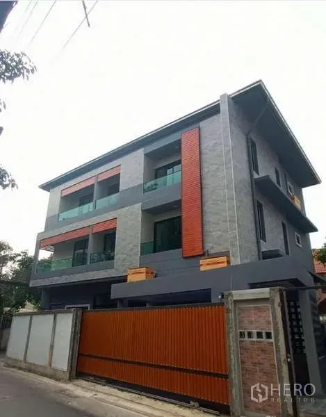 Home Office for rent in Huai Khwang, Bangkok - Modern three-storey home office with grey stone facade, orange accents and a tall sliding gate.