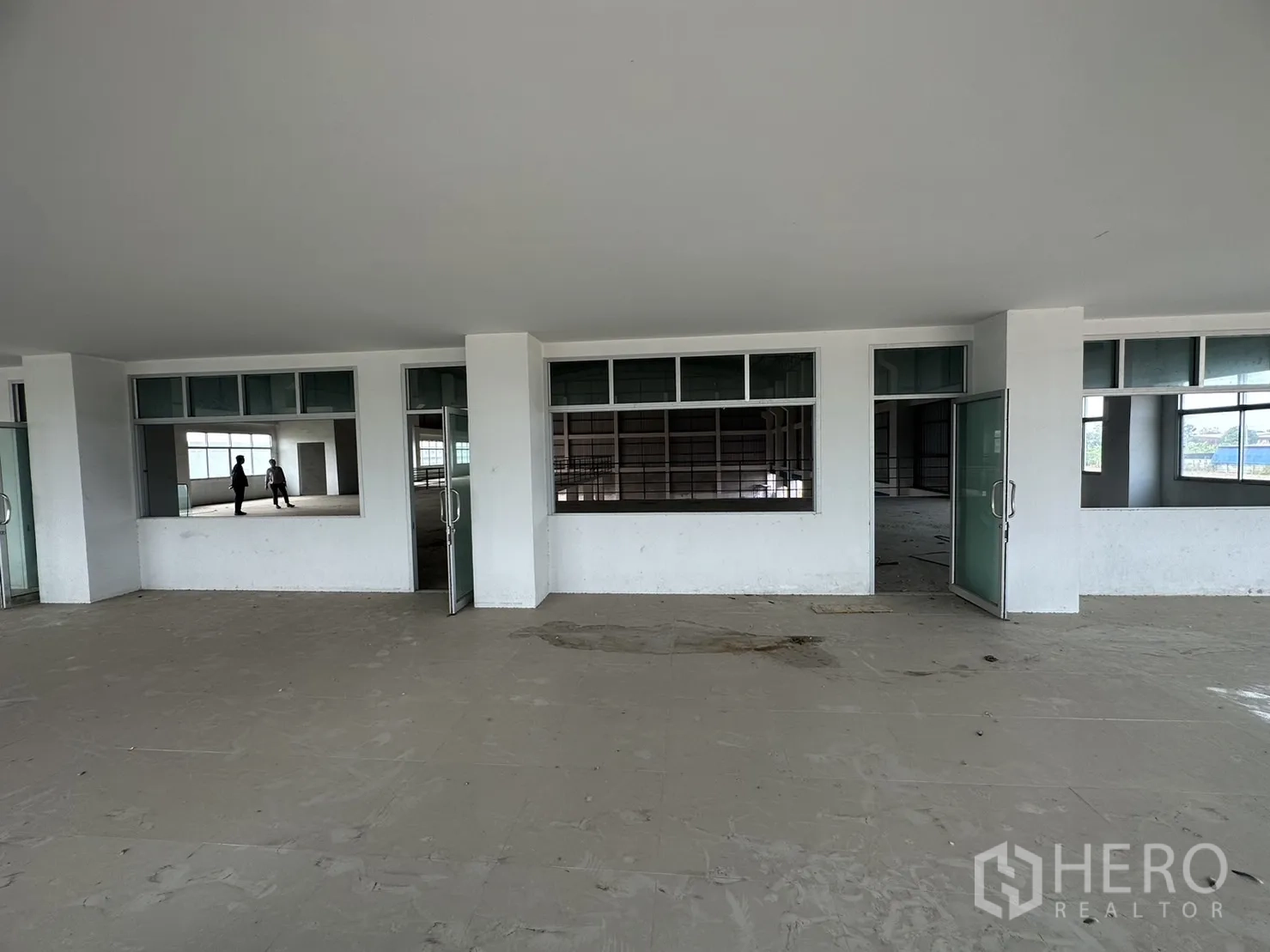 Factory for rent in Pak Kret, Nonthaburi - Row of glass doors and windows connecting office rooms to the main warehouse space.
