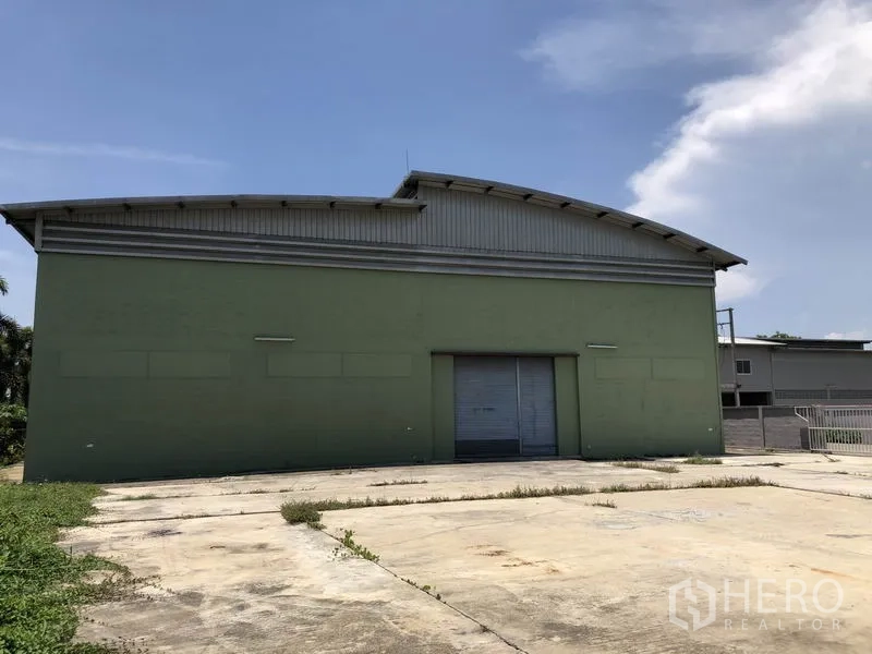 Factory for rent in Pathum Thani - Side view of factory with large roller door and wide concrete forecourt.