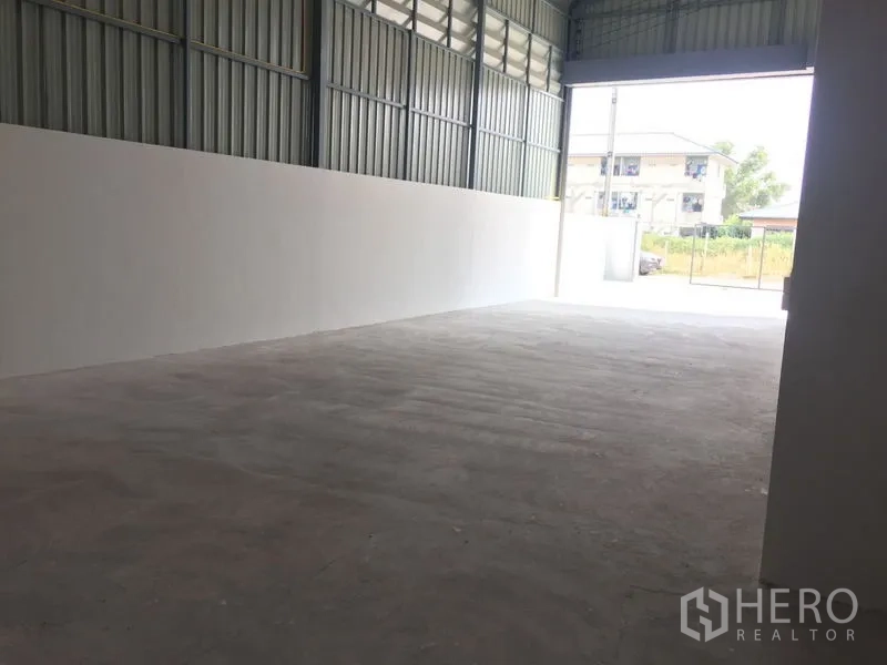 Warehouse for sale in Khlong Luang, Pathum Thani - Long storage bay with natural light facing the open roller door.