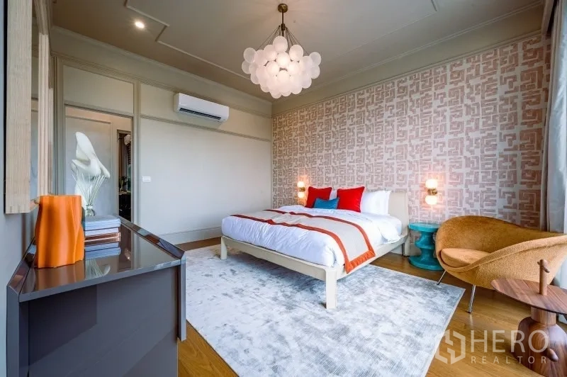 Detached House for sale in Bang Kapi, Bangkok - Colorful guest bedroom with designer chandelier, feature wallpaper and cozy armchair.