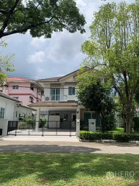Detached House for rent in Bang Kapi, Bangkok - Two-storey detached house in Bang Kapi with a gated driveway and mature trees lining the street.