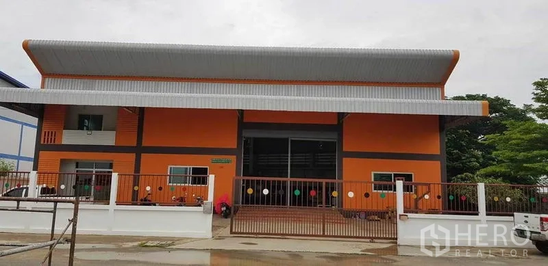 Factory for sale in Bang Phli, Samut Prakan - Front elevation of the orange factory with wide roller shutter, metal roof and secure entrance gate.