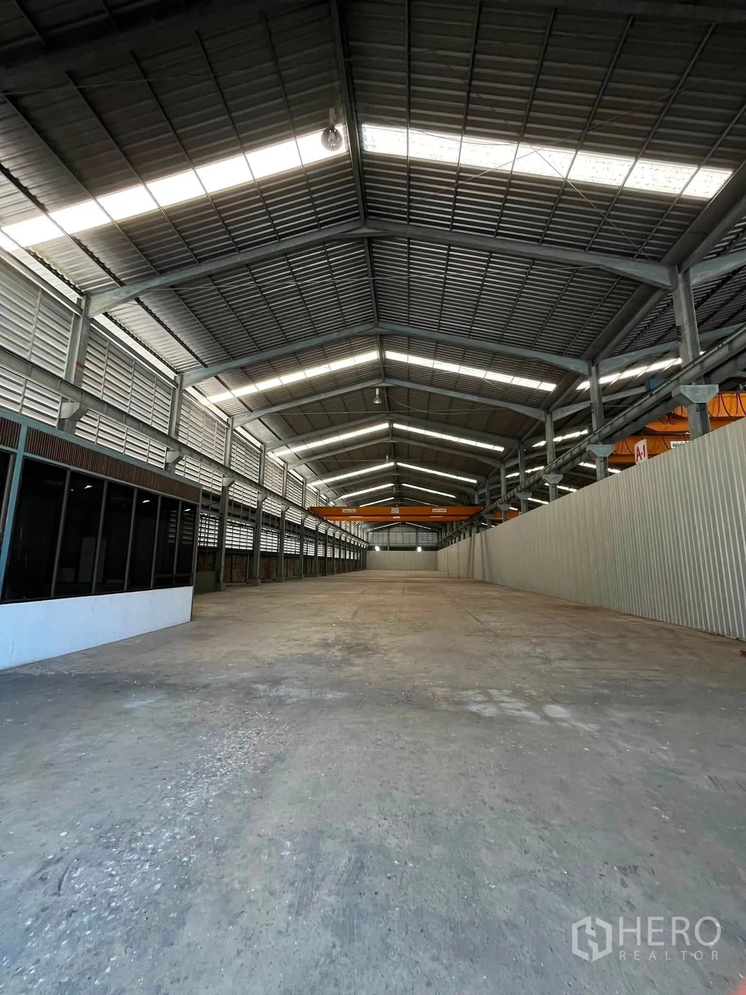 仓库 for rent in Bang Phli, Samut Prakan - 仓库中央通道，侧有办公室立面，远端可见起重机。