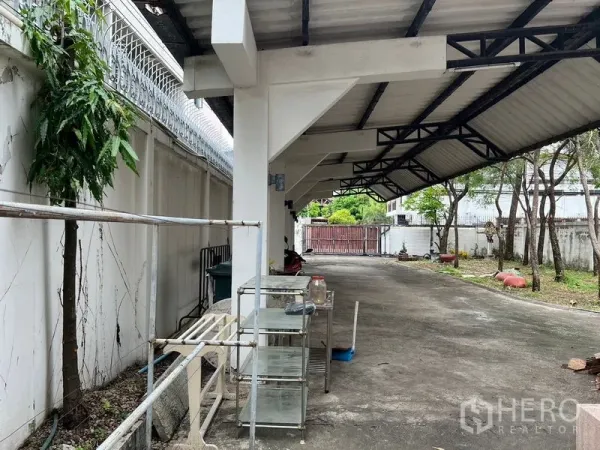 独立式住宅 出租在Sathon, Bangkok - 钢结构屋顶下的宽敞停车区，沿围墙而建。