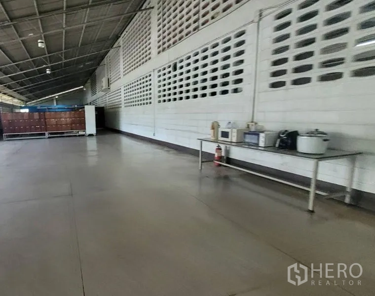 Factory for rent in Mueang Samut Prakan, Samut Prakan - Wide internal corridor with ventilation block wall, concrete floor and a utility table