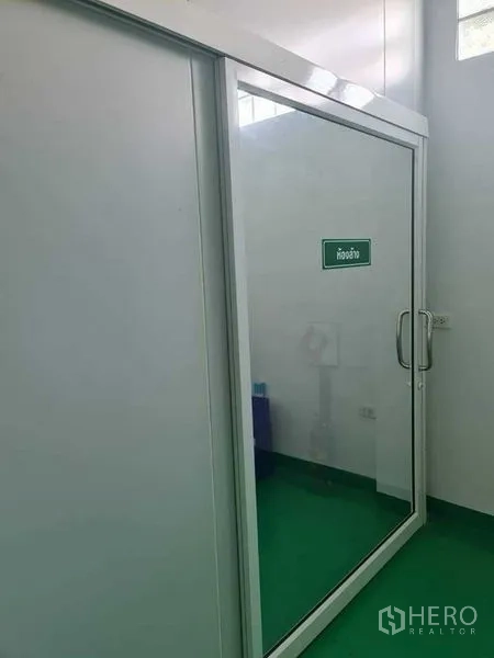 Factory for sale in Bang Pa-in, Phra Nakhon Si Ayutthaya - Glass door to the weighing room inside a white-walled factory.
