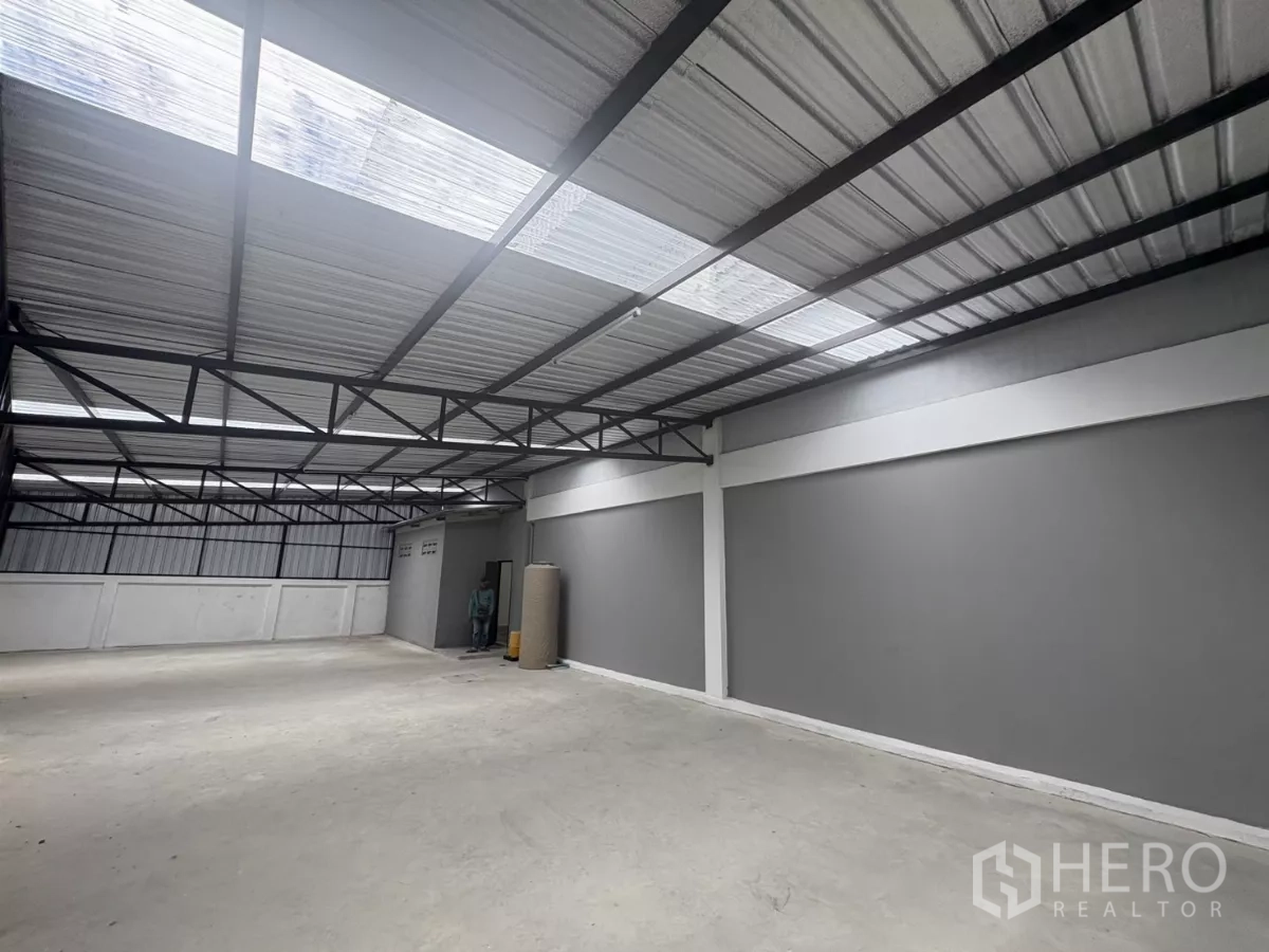 Factory for rent in Phra Samut Chedi, Samut Prakan - Alternate angle of the covered storage deck with grey walls and steel roof trusses.