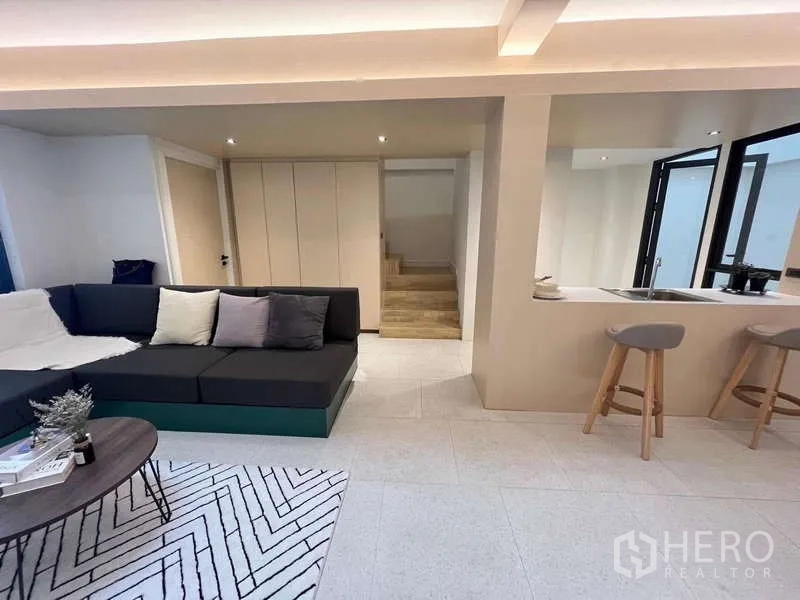 Townhouse for sale in Khlong Toei, Bangkok - Living room view toward kitchen, storage cabinets and staircase.