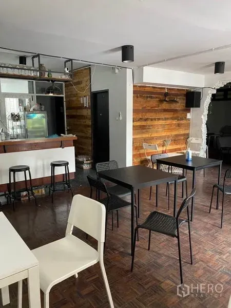 Home Office for rent in Pathum Wan, Bangkok - Ground-floor workspace with wooden accent wall, black tables and a compact bar counter.