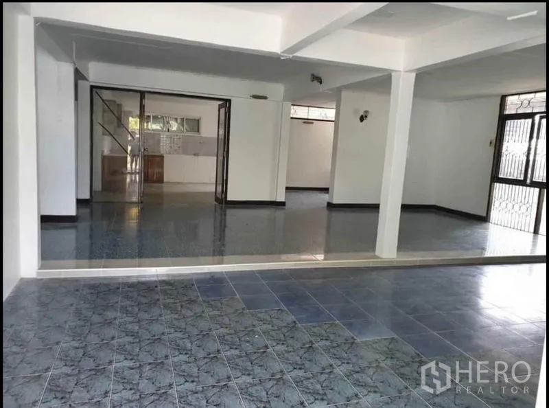 Detached House for rent in Lat Phrao, Bangkok - Open living and dining space leading to the kitchen via sliding doors and a staircase nearby.