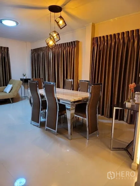 Detached House for rent - Dining area with long table, eight chairs and modern pendant lights with heavy drapes.