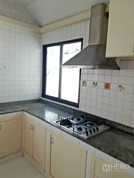 Detached House for rent in Watthana, Bangkok - Kitchen corner close-up with window, granite countertop, and gas cooktop.