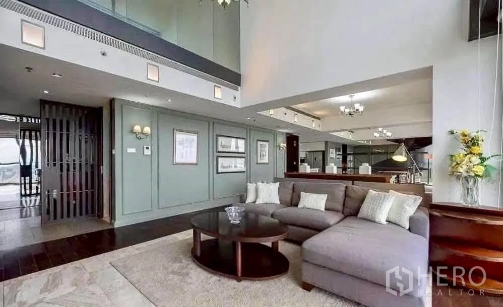 Condominium for rent in Sathon, Bangkok - Double-height living room featuring a large sectional sofa and mezzanine-style upper level.