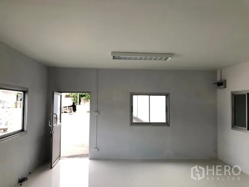 Warehouse for rent in Khlong Luang, Pathum Thani - Office entrance with sliding windows and a door opening to the yard.