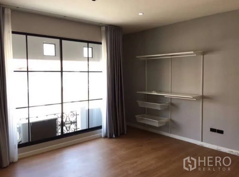 Townhouse for rent or sale in Prawet, Bangkok - Bedroom with large window, balcony railing, and built-in shelving.