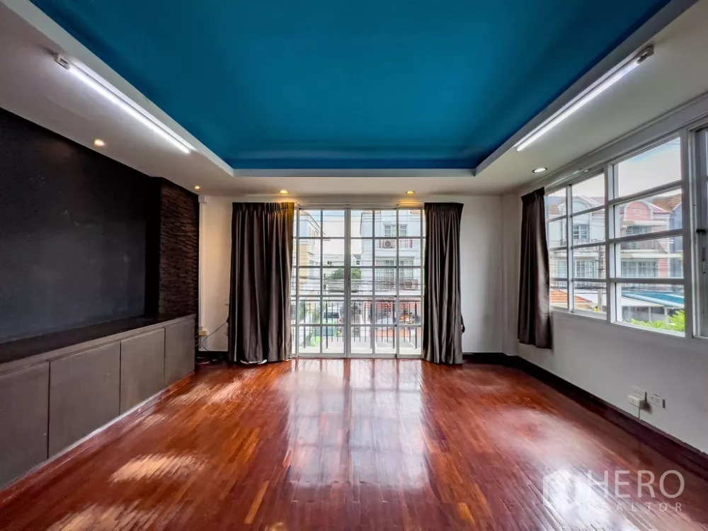Home Office for rent in Lat Phrao, Bangkok - Large open workspace with blue ceiling and balcony doors overlooking the street.