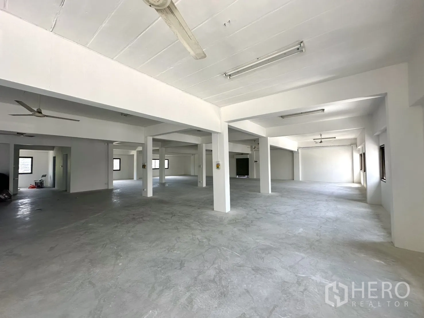 Warehouse for rent in Bang Phli, Samut Prakan - Wide warehouse floor with ceiling fans and white concrete pillars.