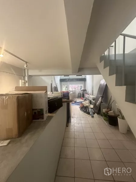 Shophouse for rent in Khlong Toei, Bangkok - Semi-finished ground floor with stairs, storage area, and renovation materials.