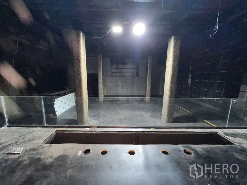 店屋 出租 - 深色开放大厅，圆形立柱与玻璃护栏。