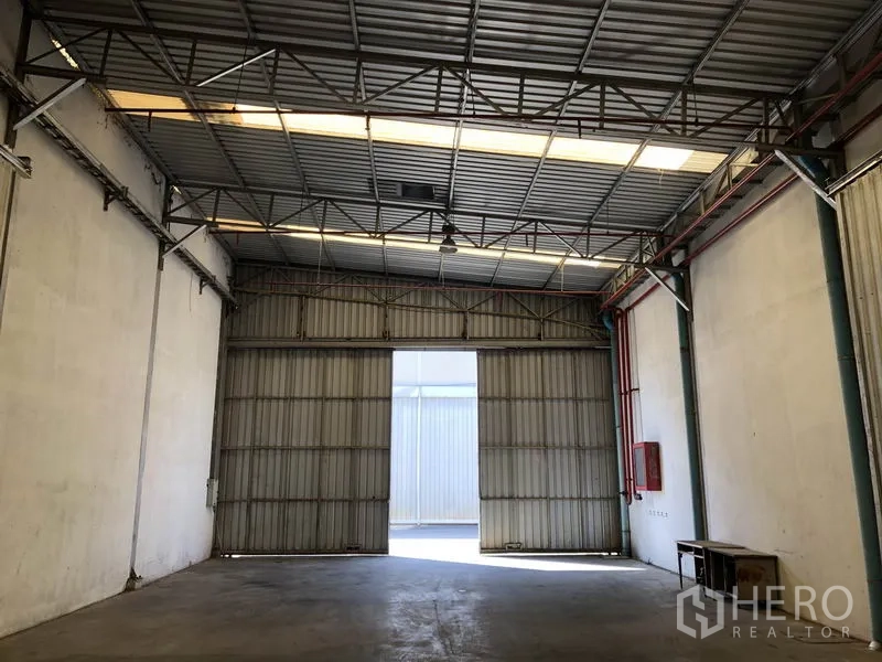 Warehouse for rent in Bang Bua Thong, Nonthaburi - Warehouse entrance with tall folding steel doors and a visible fire hose cabinet.