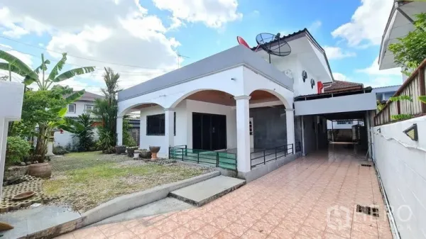 Detached House for rent in Lat Phrao, Bangkok - Two-storey detached house in Lat Phrao with arched porch, long tiled driveway and front garden under blue sky.