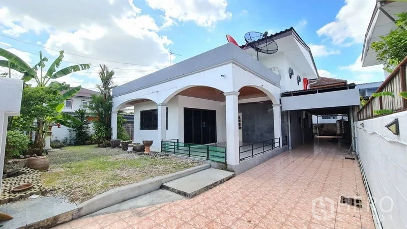 Detached House for rent in Lat Phrao, Bangkok - Two-storey detached house in Lat Phrao with arched porch, long tiled driveway and front garden under blue sky.