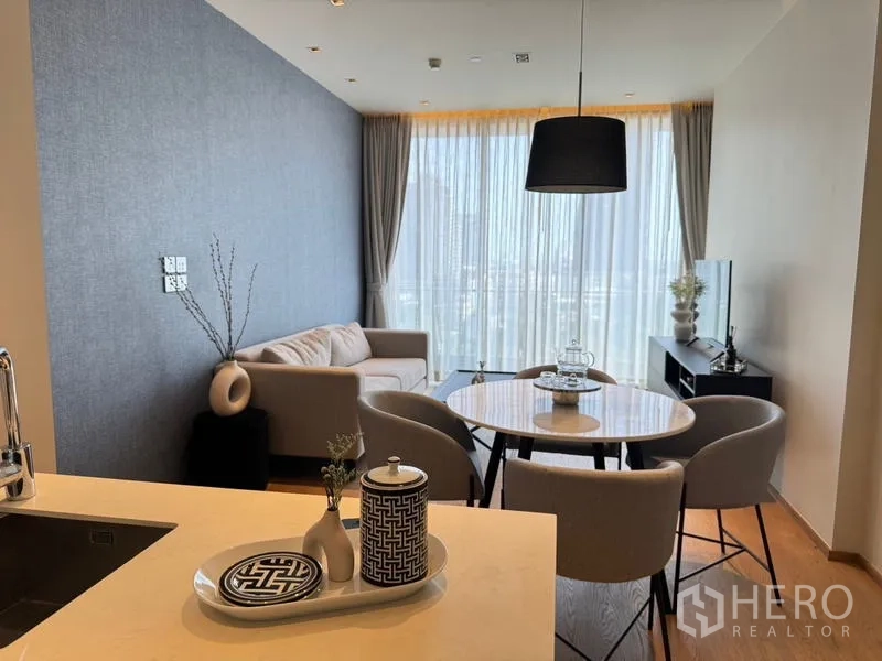 Condominium for rent - Bright living and dining area with round table, sofa, and floor-to-ceiling sheer curtains.