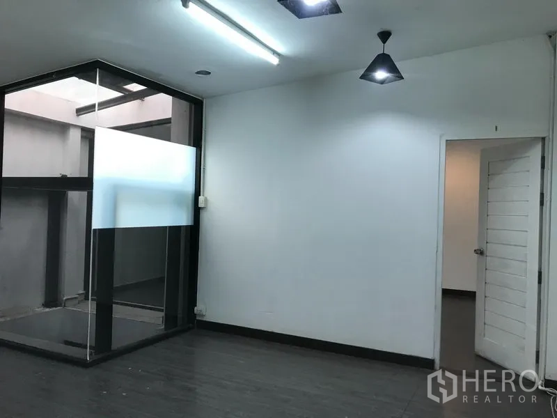 Shophouse for rent in Watthana, Bangkok - Room with ceiling lights and a corner glass atrium with a frosted panel beside an open door.