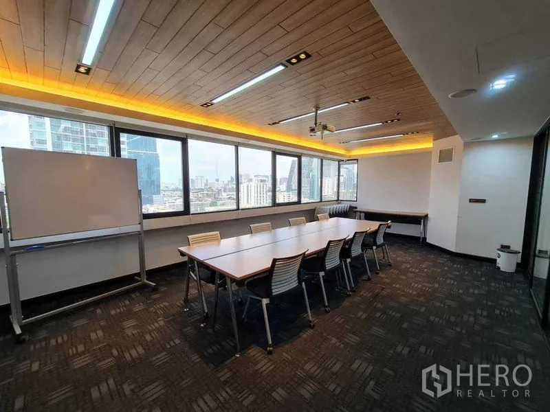 Office Space for rent - Training room with long tables, whiteboard and expansive skyline views through large windows.