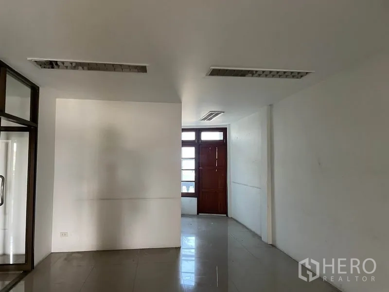 Warehouse for rent in Prawet, Bangkok - Open office area with tiled floor, recessed lights, and a solid wooden rear door.