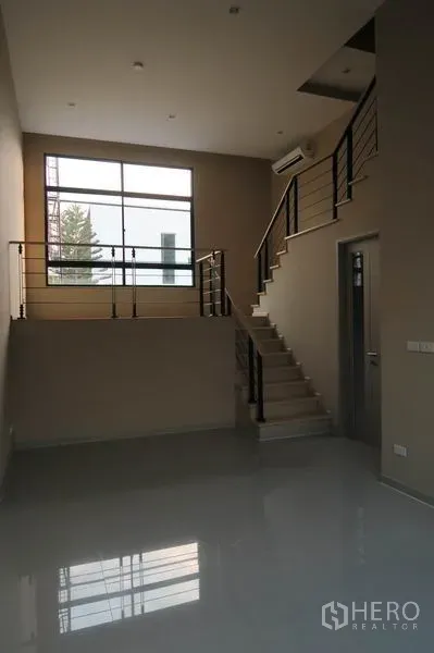 Townhouse for rent in Suan Luang, Bangkok - Mezzanine-style living space with staircase, metal railings, and a large window.