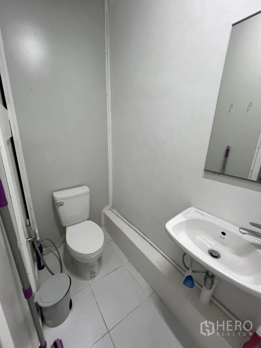 Shophouse for rent or sale in Khlong Toei, Bangkok - Compact bathroom with toilet, sink and wall mirror.