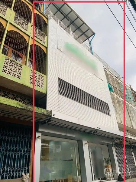 Shophouse for rent or sale in Khlong Toei, Bangkok - Modern narrow shophouse facade with white cladding and a glass-fronted ground floor in a row of townhouses.