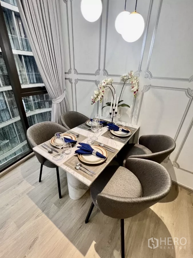Condominium for rent in Khlong Toei, Bangkok - Marble-top dining table set for four with pendant lights and grey chairs.