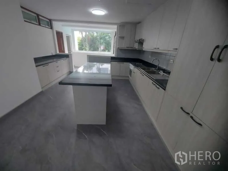 Condominium for rent in Watthana, Bangkok - Fully fitted kitchen with island, light cabinetry, black countertops and window views.