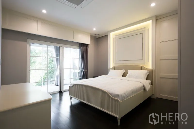 Detached House for rent in Mueang Samut Prakan, Samut Prakan - Cozy bedroom with illuminated feature headboard and sliding glass doors opening to a garden terrace.