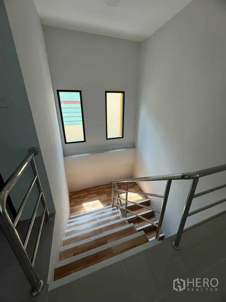 Factory for sale in Samut Sakhon - Bright stairwell with stainless handrail and slim vertical windows.