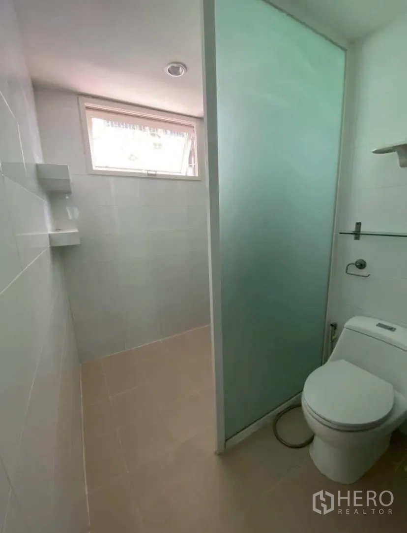 Townhouse for rent in Phra Khanong, Bangkok - Bathroom with frosted glass partition, toilet, and high window for ventilation.