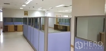 办公空间 出租或出售在Bang Rak, Bangkok - 开放式办公室区域，蓝色隔断工位与顶置照明。
