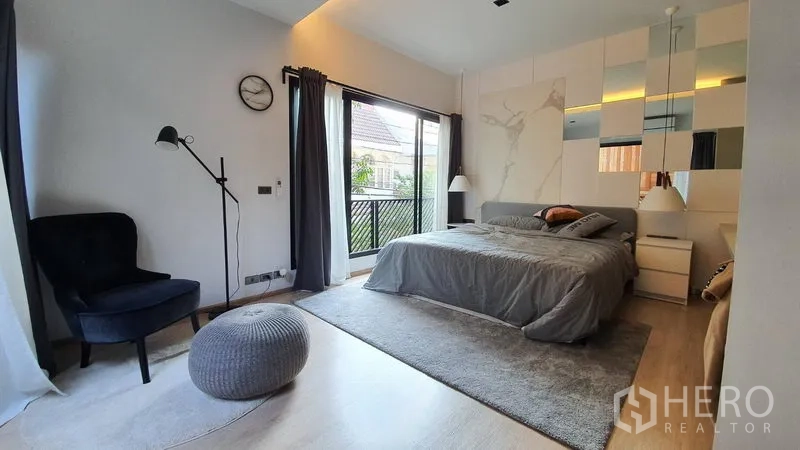 Townhouse for rent in Khlong Toei, Bangkok - Spacious master bedroom with large bed, balcony access via sliding doors, and soft lighting.