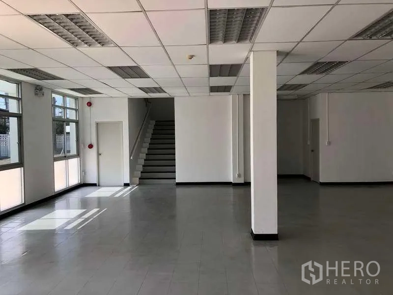 Factory for rent or sale in Phra Nakhon Si Ayutthaya - Bright ground-floor office area with tiled flooring, windows and a staircase.