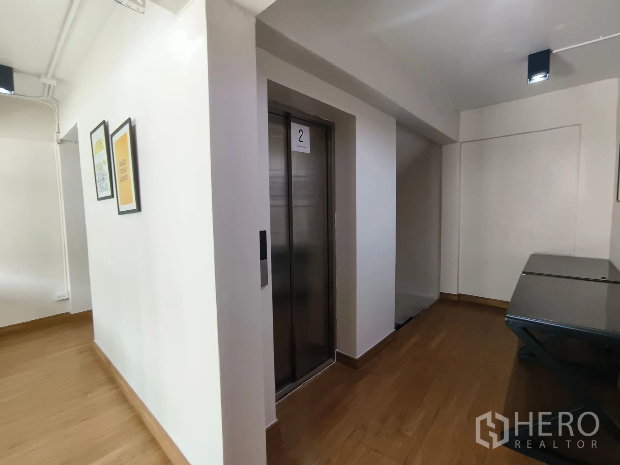Shophouse for rent in Watthana, Bangkok - Elevator lobby with lift doors, framed posters and wood flooring.