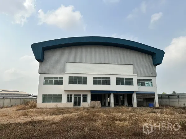 Factory for rent in Pak Kret, Nonthaburi - Front elevation of the factory highlighting office windows and a wide roller shutter entry.