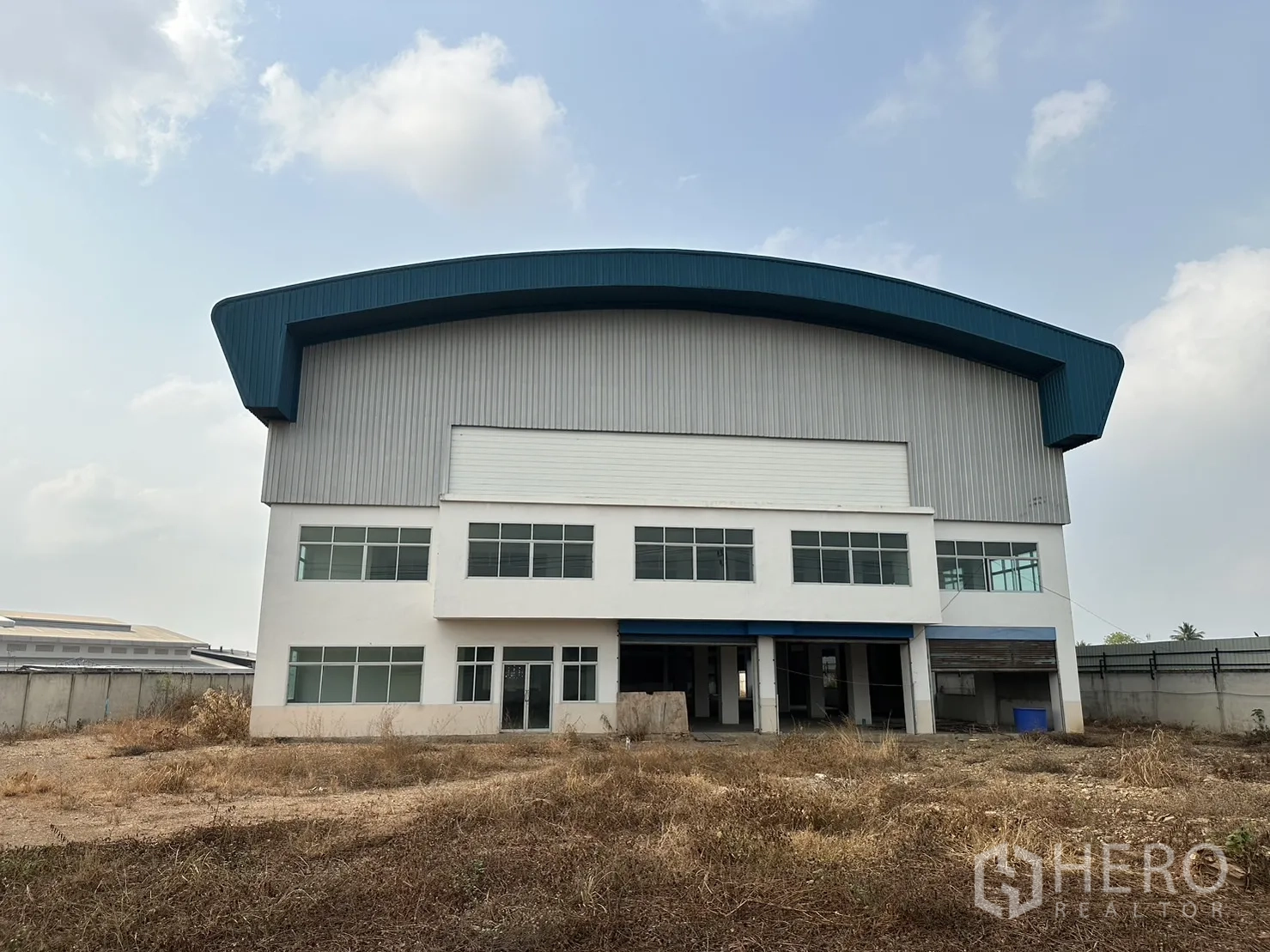Factory for rent in Pak Kret, Nonthaburi - Front elevation of the factory highlighting office windows and a wide roller shutter entry.
