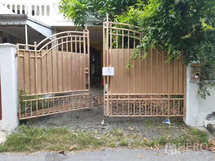 Townhouse for rent in Khlong Toei, Bangkok - Gated townhouse entrance with gold metal gate, leafy trees and a paved driveway.