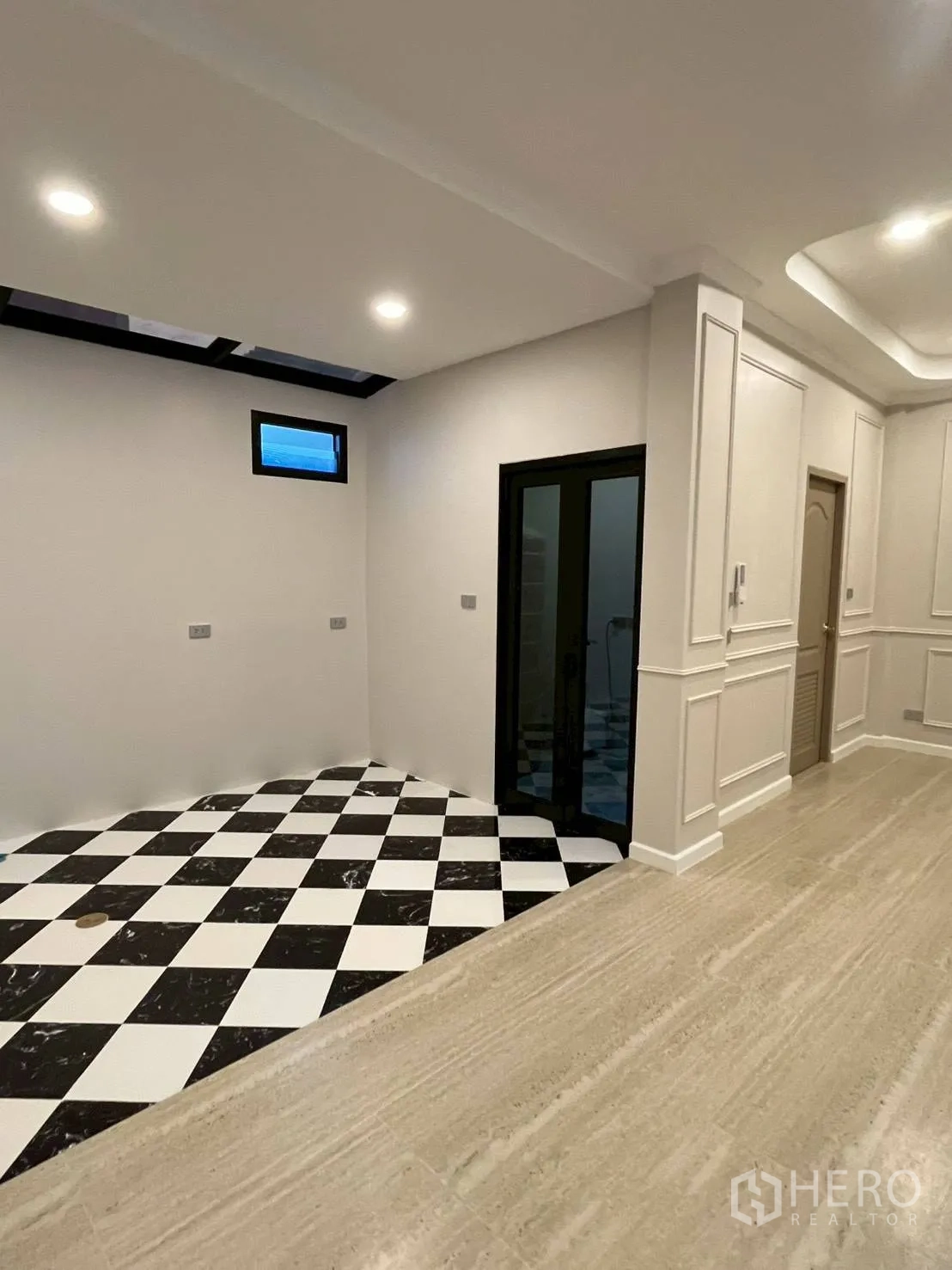 Townhouse for rent in Khlong Toei, Bangkok - Kitchen area with black-and-white checkered tiles, sliding glass door, and ceiling spotlights.